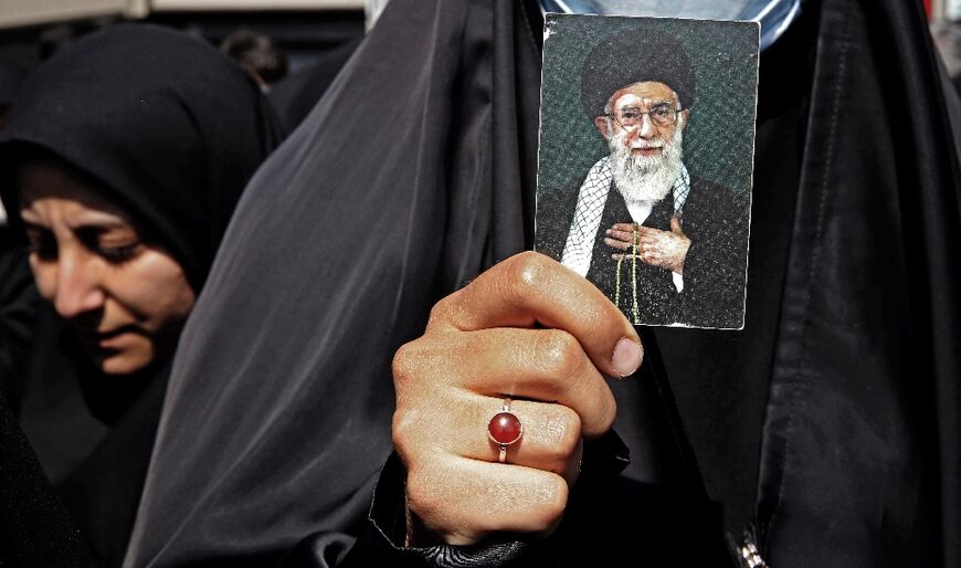 A woman counter-demonstrator shows her loyalty to Iran's supreme leader Ayatollah Ali Khamenei by clasping a photgraph of him