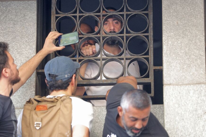 Abed Soubra, a depositor demanding to withdraw his frozen savings, speaks from the window of the Blom Bank branch in the capital Beirut's Tariq al-Jdideh neighbourhood on Friday