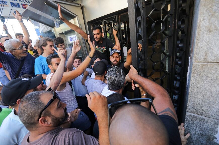 People outside a branch of Blom Bank branch in the capital Beirut's Tariq al-Jdideh neighbourhood express their support for a depositor demanding his savings