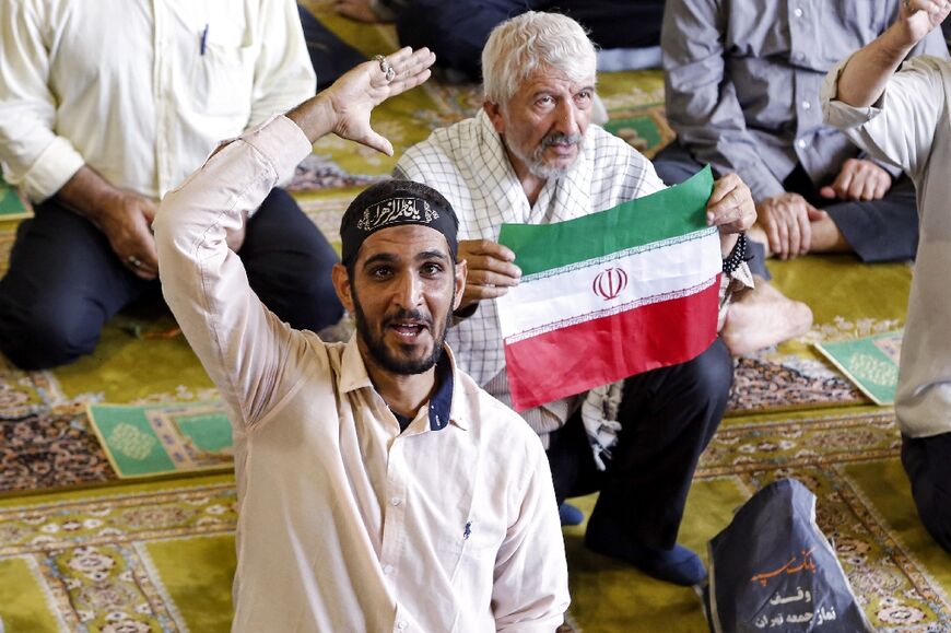 A man holds up an Iranian flag while worshippers chant slogans during weekly prayers at a mosque in Tehran