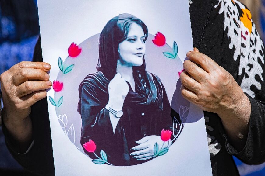 A woman holds up a picture of Mahsa Amini, the young Iranian woman who died while in Iranian police custody, at a solidarity demonstration in Syria's northeastern city of Hasakeh 