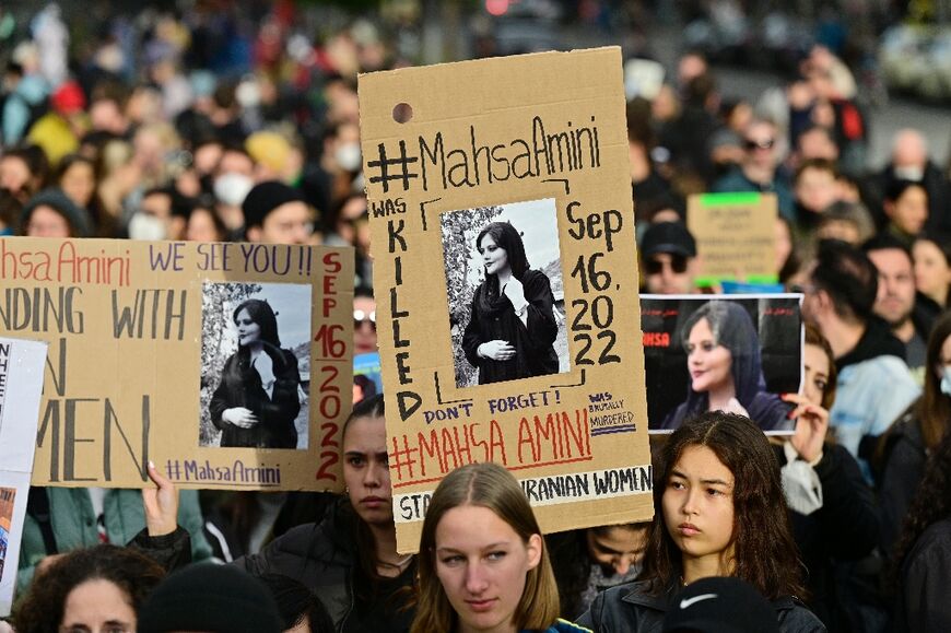 Demonstrators in Berlin hold up placards with images of Mahsa Amini in Berlin