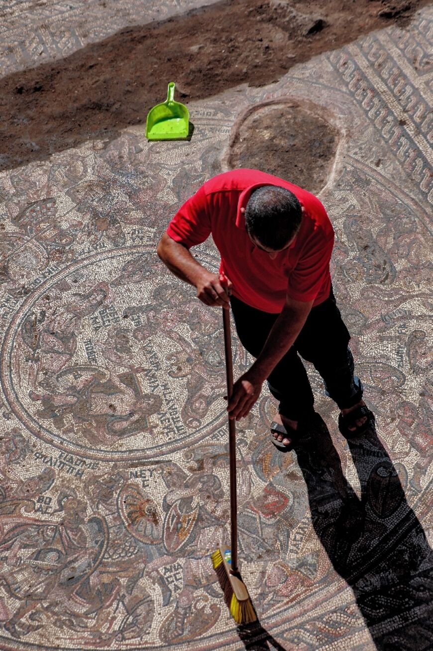 A man sweeps dirt off a mosaic floor discovered in Rastan in northern Syria's Homs district  