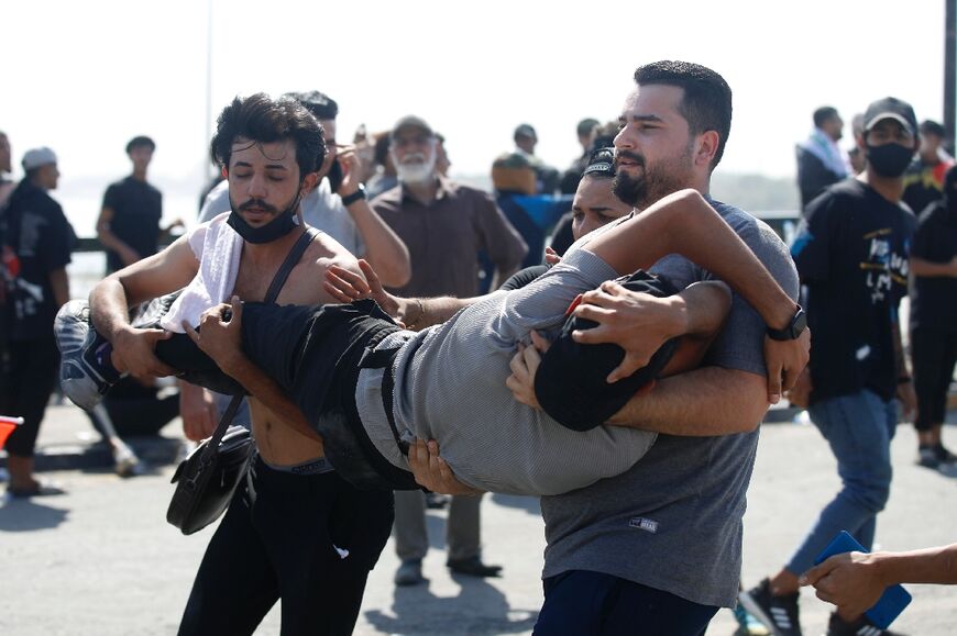 Iraqi anti-government demonstrators evacuate a wounded man during clashes with security forces after a protest on the Jumhuriya (Republic) bridge leading to the capital Baghdad's high-security Green Zone on October 1, 2022