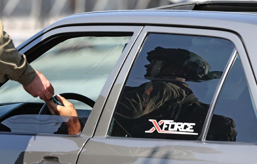 An Israeli soldier checks the ID of a driver as troops deploy in the Deir Sharaf area west of Nablus in the occupied West Bank on October 11 following a reported attack