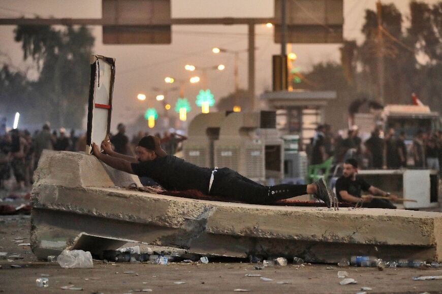 A supporter of Iraqi Shiite cleric Moqtada Sadr takes cover in the capital Baghdad, in clashes on August 29, 2022