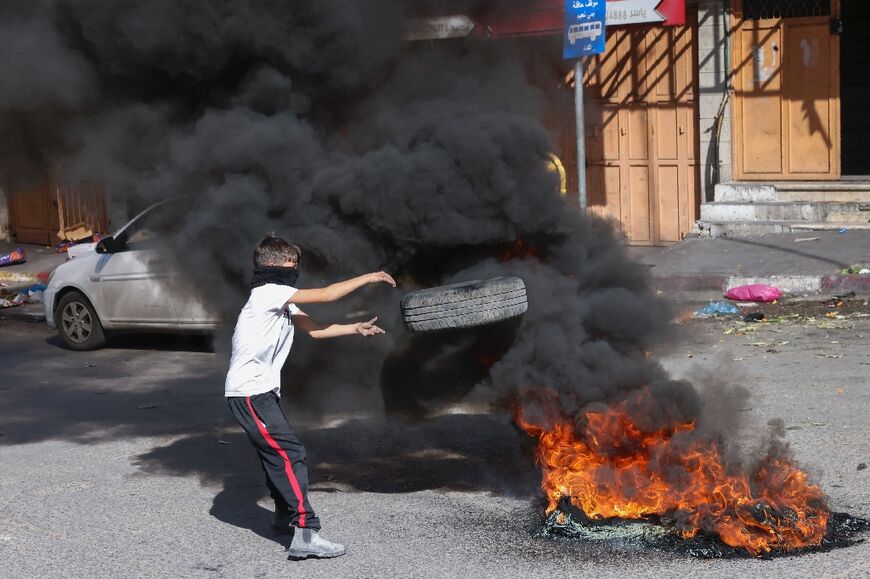 Palestinian protesters burn tyres during clashes with Israeli security forces at a checkpoint in the centre of Hebron city in the occupied West Bank, on November 11, 2022