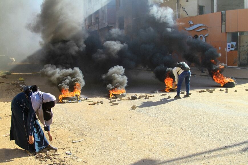 Tyres were set on fire by protesters angry at last year's military coup in Sudan to block roads in Khartoum