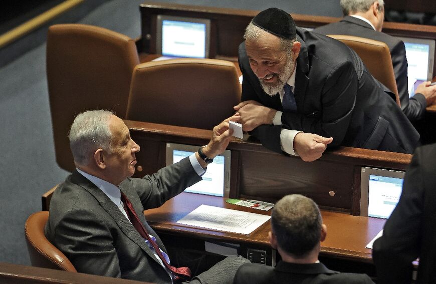Israeli prime minister-designate Benjamin Netanyahu (L) speaks with key ally Aryeh Deri of the ultra-Orthodox Jewish party Shas, as they prepare to fast-track a change to the law to allow Deri to serve in cabinet despite past tax evasion convictions