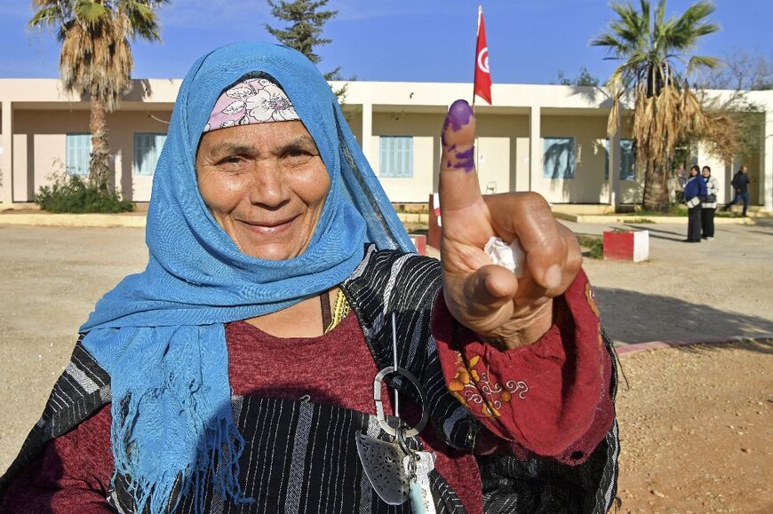 A Tunisian voter shows her ink-stained finger after voting in the parliamentary election, at a polling station in Mnihla district outside Tunis on December 17 