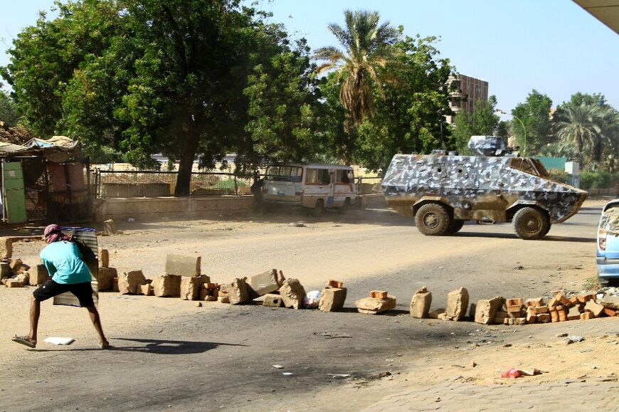 A demonstrator takes cover behind a makeshift shield during clashes with security forces in Sudan's capital