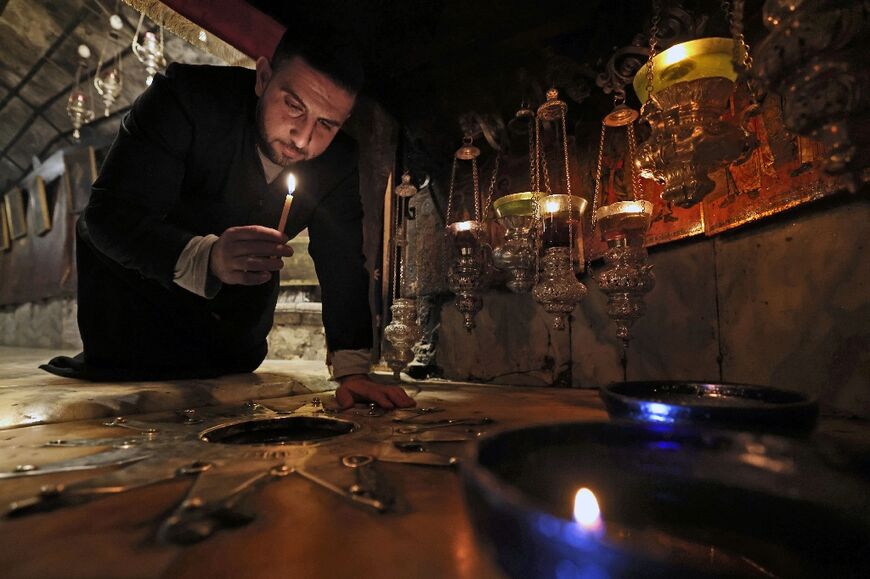 A Christian worshipper kneels next to a 14-pointed silver star, believed to be the exact spot where Jesus Christ was born, at the grotto in the Church of the Nativity