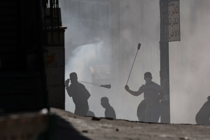 Palestinian demonstrators hurl rocks toward Israeli troops during confrontations with them in the West Bank town of Al-Ram on January 27