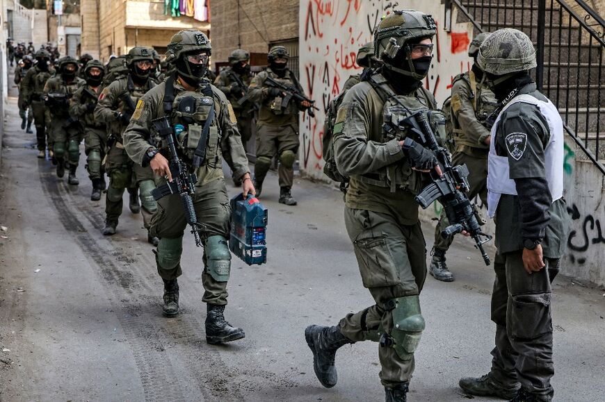Israeli soldiers walk in file after a demolition operation in east Jerusalem's Shuafat refugee camp on January 25