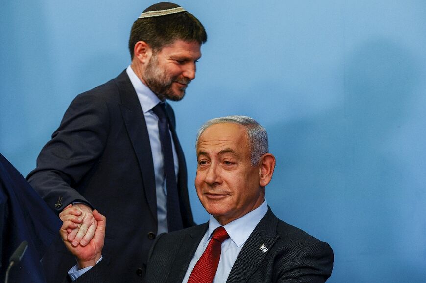 Israeli Finance Minister Bezalel Smotrich, on the left, shakes the hand of Prime Minister Benjamin Netanyahu during a press conference at the Prime Minister's office in Jerusalem on January 25, 2023