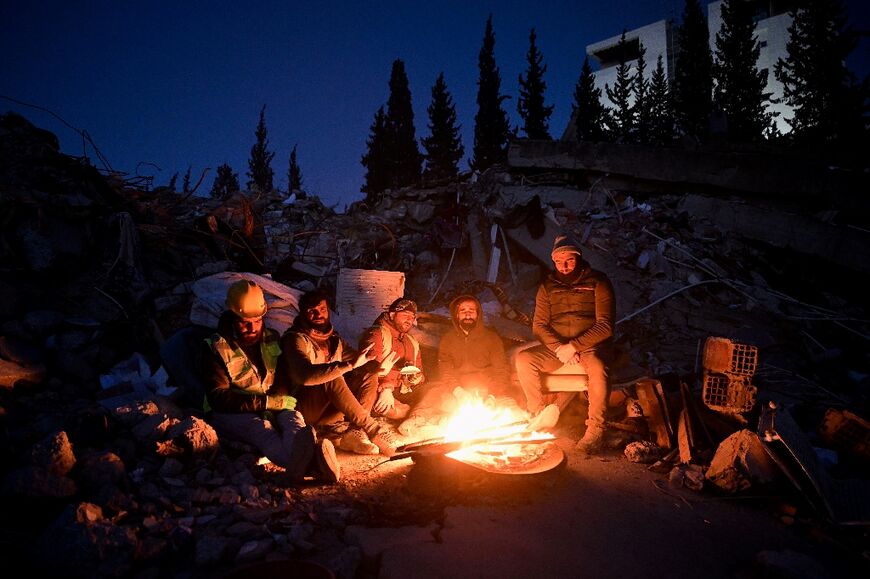 Survivors seek warmth around a fire