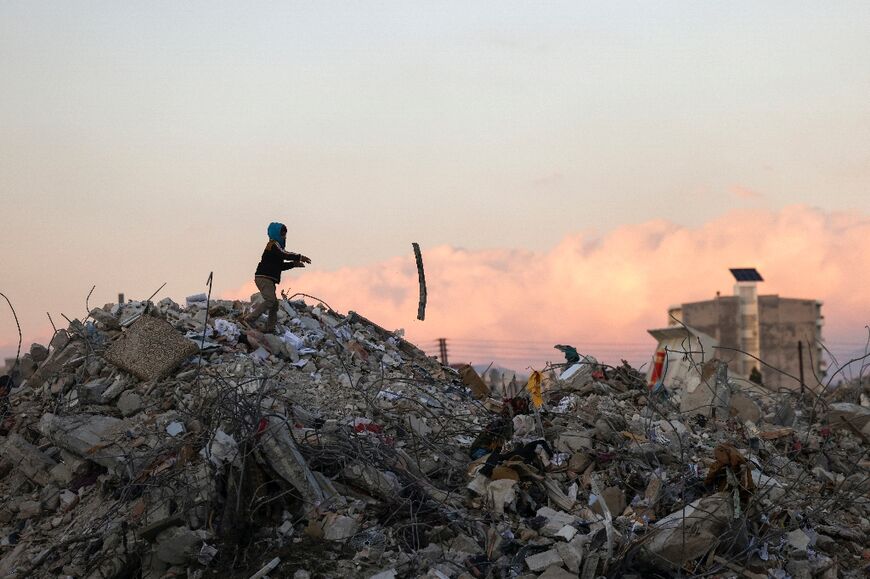 A Syrian boy searches through the rubble for items to salvage in Jableh