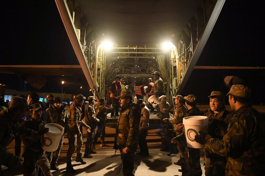 Syrian soldiers unload relief supplies sent by  Iraq at Aleppo airport on February 8, 2023 