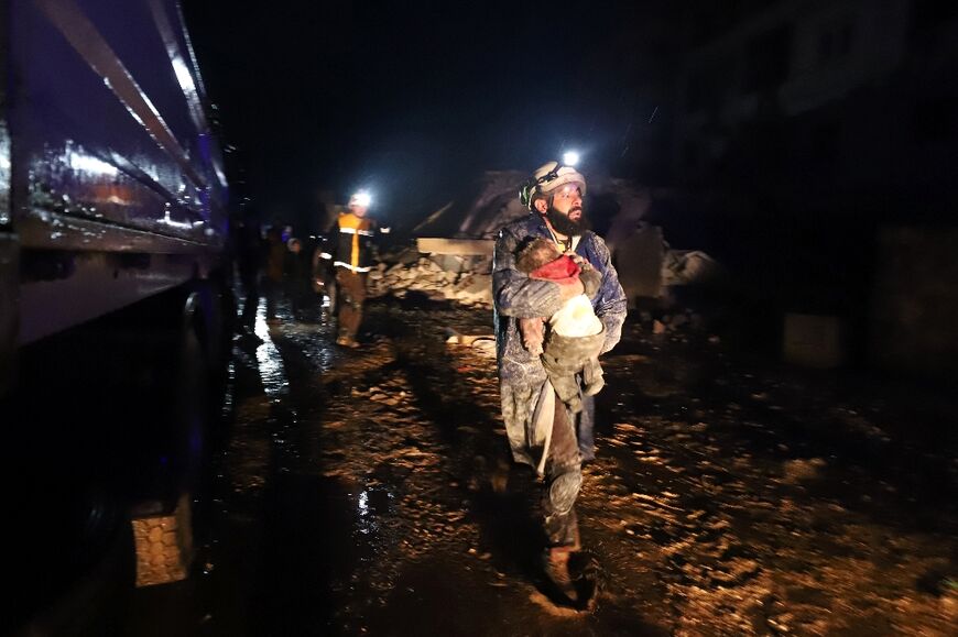 A member of Syria's White Helmets civil defence group carries a child rescued from rubble in the town of Zardana in Idlib province