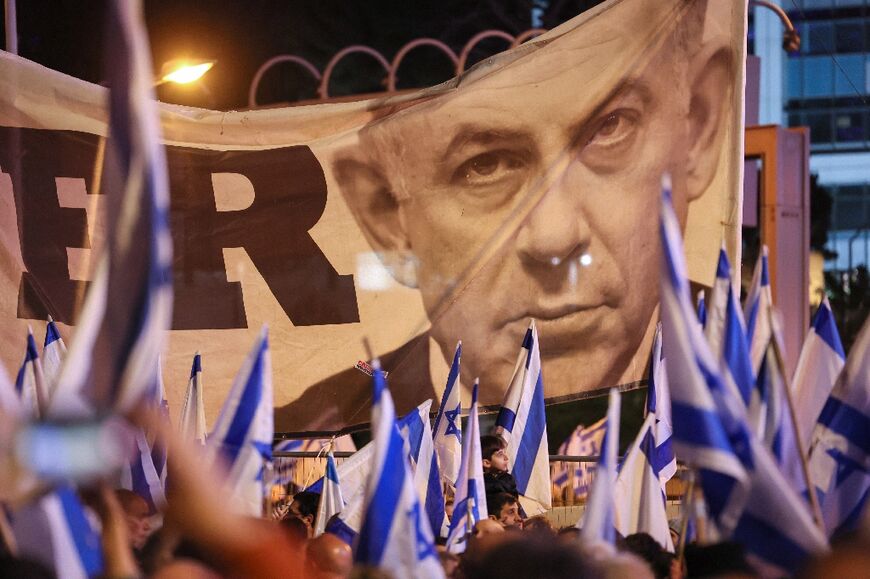 Israeli protesters wave flags as they rally in central Tel Aviv, on February 11 against controversial legal reforms 