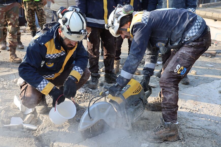 White Helmets rescuers cut through a block of cement in the Syrian town of Jindayris
