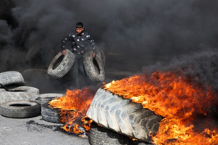 Palestinian protesters burn tyres to block a road into Jericho following the February 6, 2023 raid in the town by Israeli forces