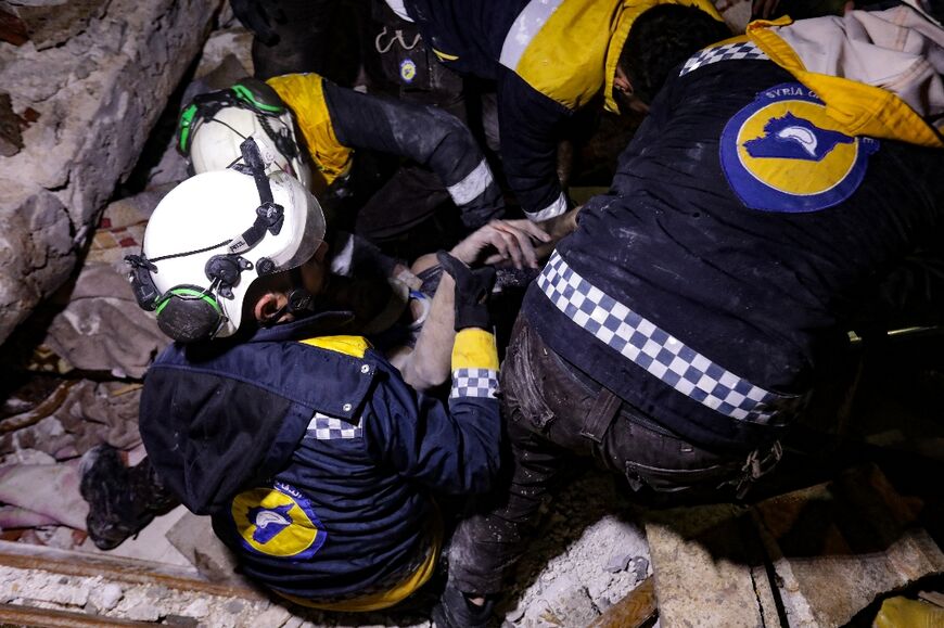 White Helmets rescuers work to retrieve a man from the rubble of a collapsed building in Syria's Azaz