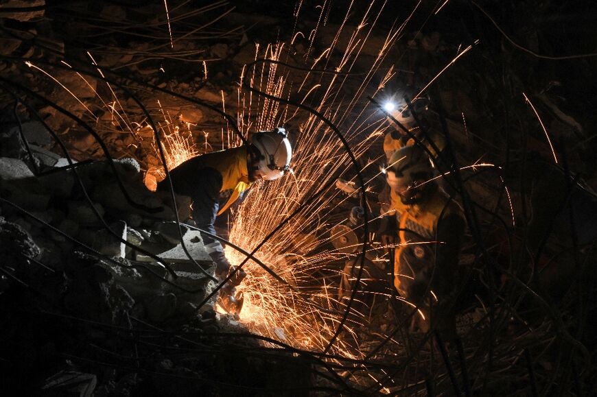 Sparks fly as members of the Syria Civil Defense work work to remove rubble in the town of Jindayris