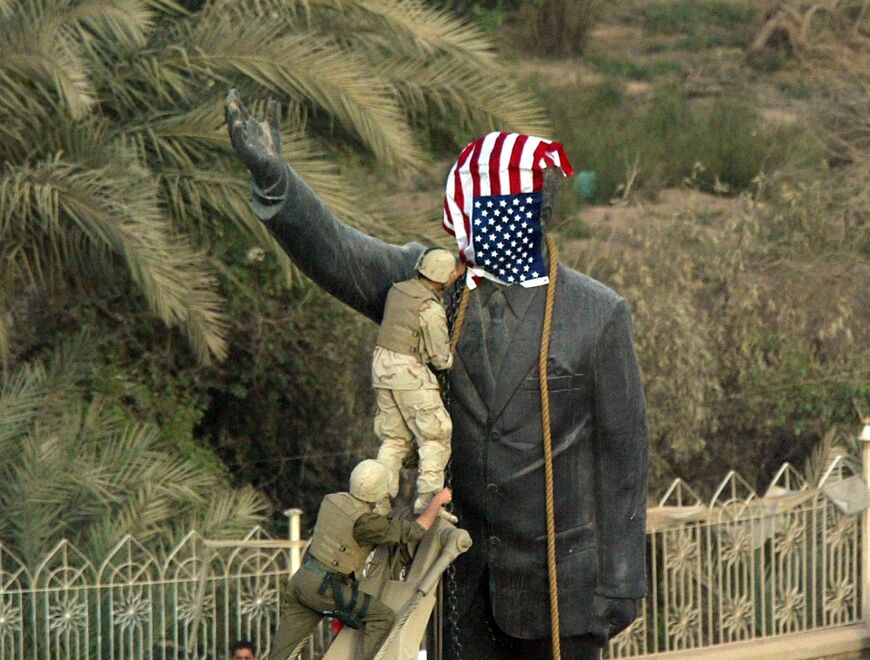 US Marines cover the statue of Iraqi President Saddam Hussein in Baghdad on April 9, 2003 as they prepare to bring it down -- but shortly afterwards replaced their flag with an Iraqi one