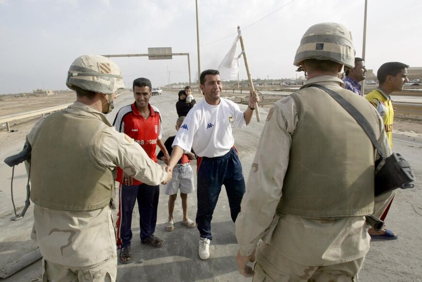An Iraqi man waving a white flag shakes hands with a US Marine at a Baghdad roadblock one day after Iraqi president Saddam Hussein's regime collapsed, in this file photo from April 10, 2003 