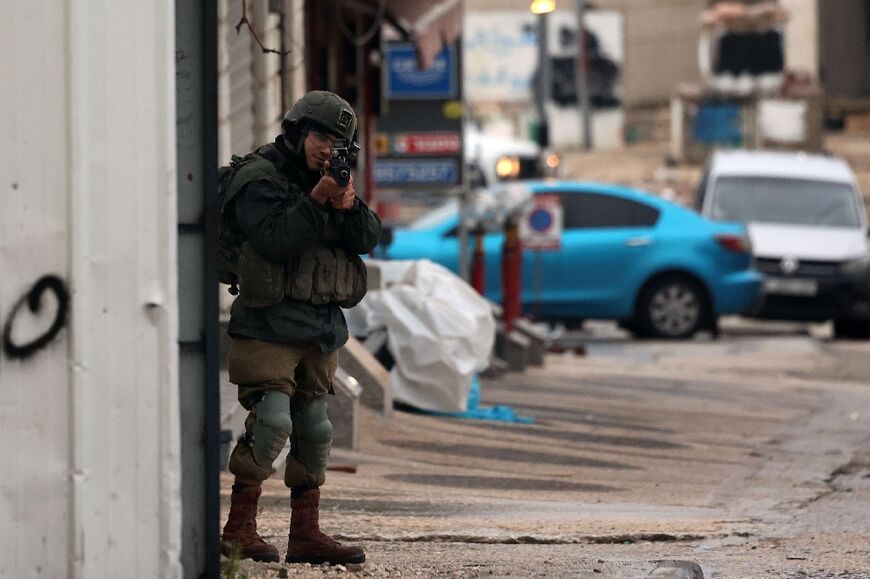 An Israeli soldier holds a position in Huwara following a shooting that wounded one Israeli