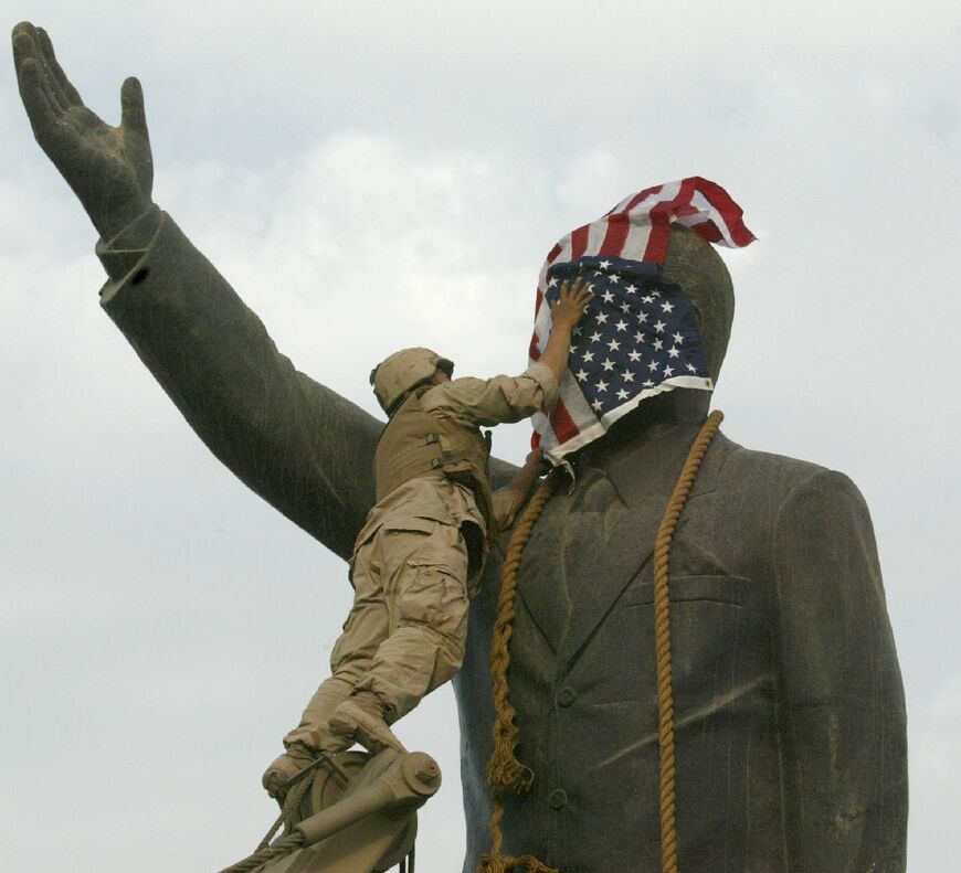 A US Marine covers the face of Iraqi president Saddam Hussein's statue with the US flag in Baghdad's al-Fardous square 9 April 2003