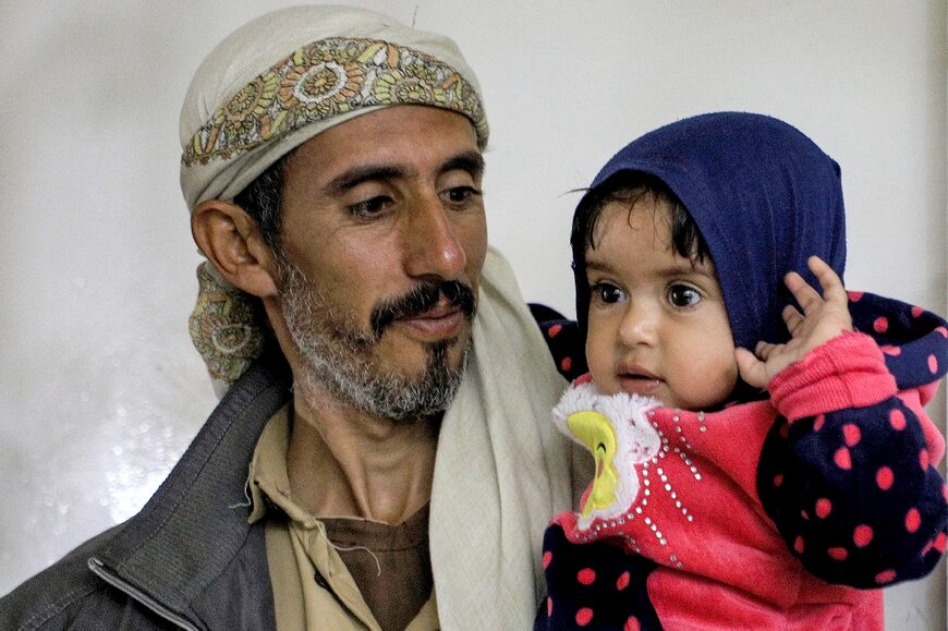 A man carries a child at al-Janatain Charity Medical Centre  in Yemen's Huthi-rebel-held capital Sanaa on March 14, 2023