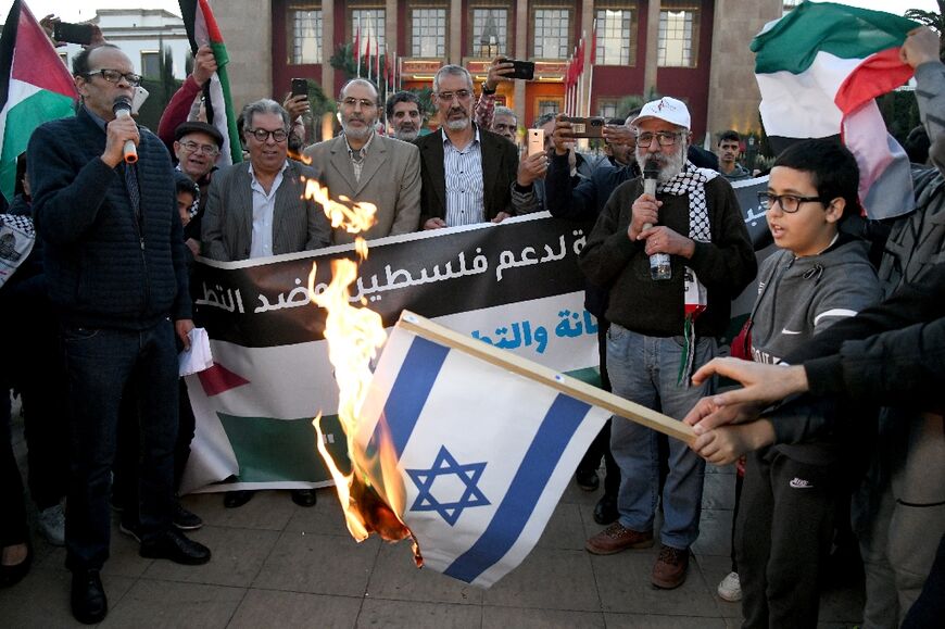 Moroccans burn the Israeli flag as they gather to protest the normalisation of ties with Israel, outside the parliament building in the capital Rabat on December 24, 2022 