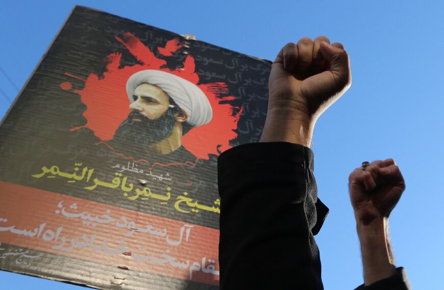 Iranian protesters raise their fists in front of a portrait of prominent Shiite Muslim cleric Nimr al-Nimr during a demonstration against his execution by Saudi authorities, on January 3, 2016