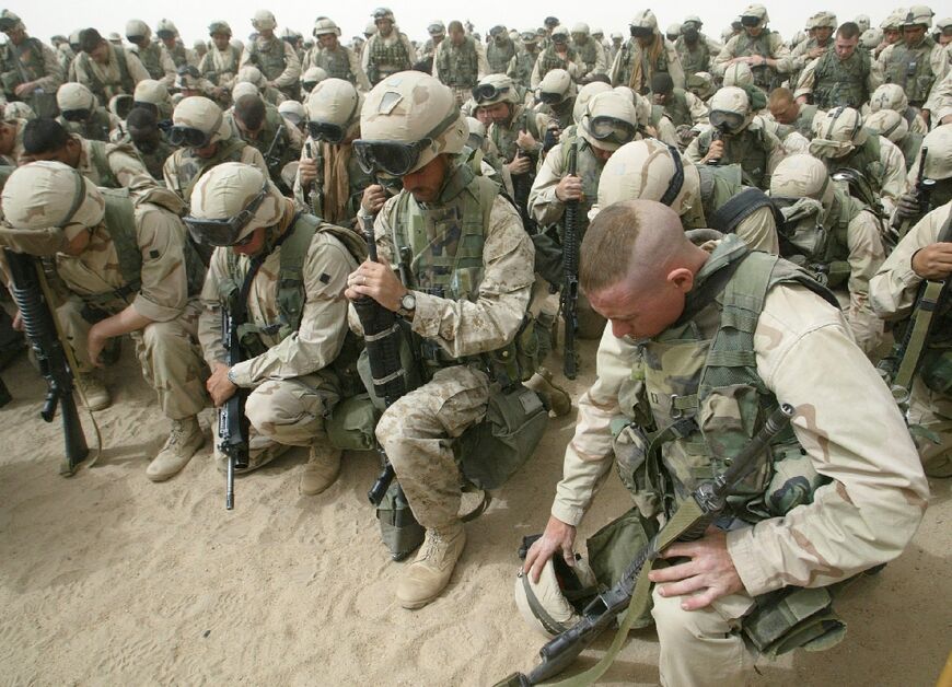 US Marines pray as they prepare to leave Camp Shoup, north of Kuwait City, to start their advance into southern Iraq, in this file photo from March 20, 2003 