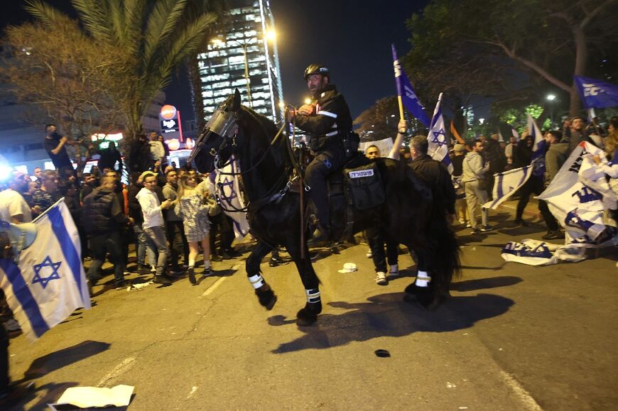 An Israeli mounted policeman is deployed around protesters in Tel Aviv