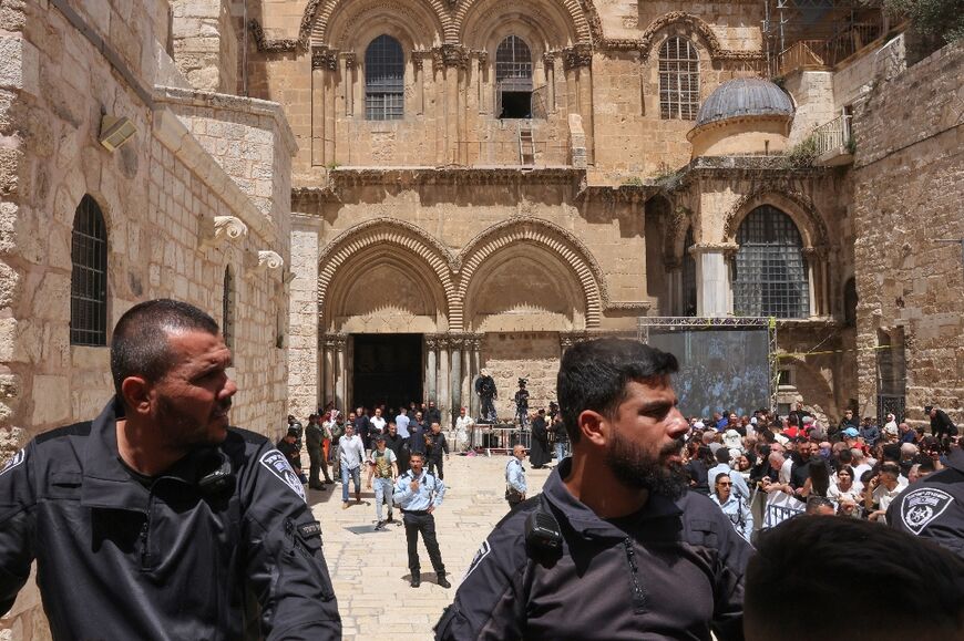 Israeli police outside the Church of the Holy Sepulchre in Jerusalem as Christians  wait behind a barrier before the Holy Fire ceremony