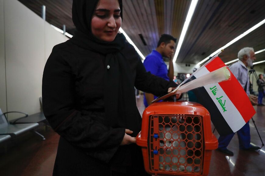 A woman evacuated from Sudan holds her pet cat as she arrives at Baghdad International Airport on April 27