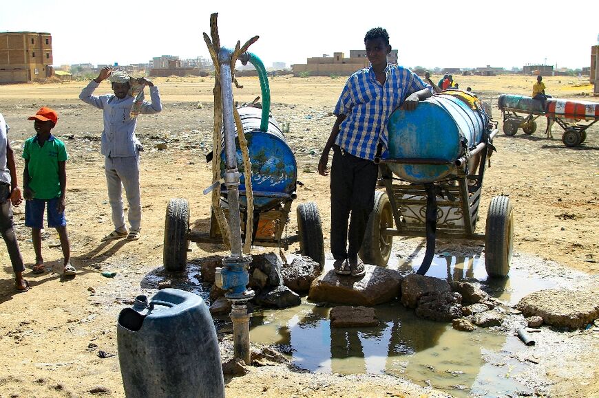 People fill barrels with water in Khartoum amid water shortages caused by ongoing battles between the forces of two rival generals