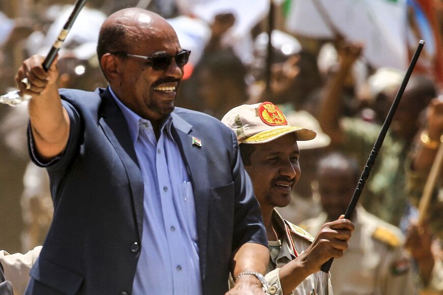 Omar al-Bashir, left, pictured in 2017 when he was president, waves a walking stick as he tours Dafur with the commander of the Rapid Support Forces (RSF) paramilitaries Mohamed Hamdan Daglo