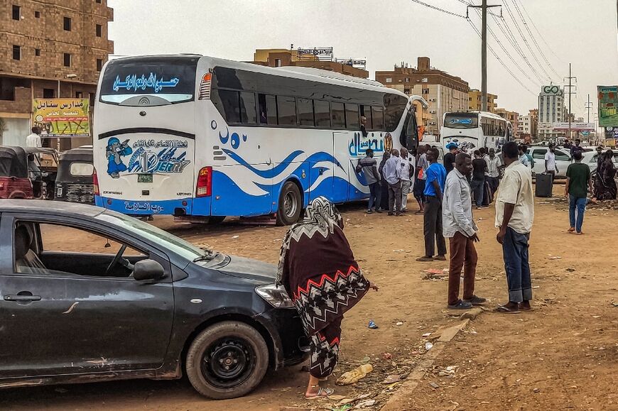 People prepare to board a bus departing from Khartoum in the Sudanese capital's south on April 24, 2023, as battles rage in the city between the army and paramilitaries