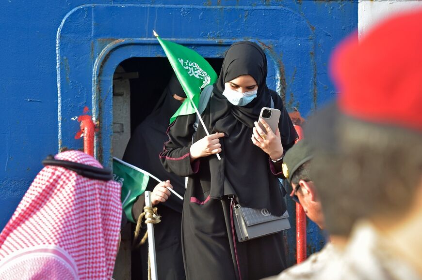 Saudi naval personnel help civilians off the evacuation ship after it docks at the King Faisal base in Jeddah