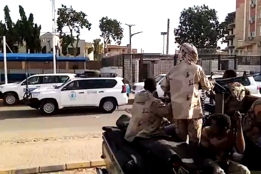 A convoy evacuating foreign citizens leaves Khartoum towards Port Sudan watched by soldiers
