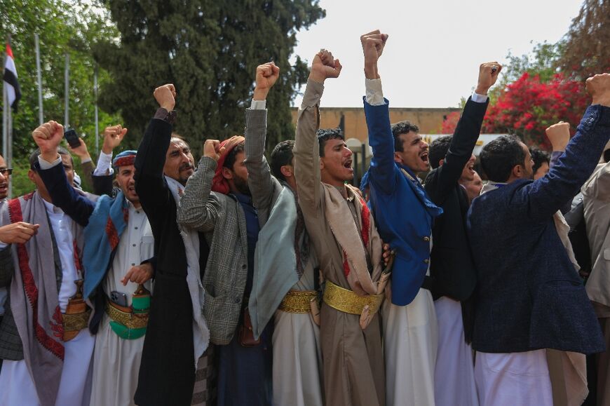 Men gesture and chant during a welcome ceremony for Yemeni Huthi rebel prisoners upon their arrival at Sanaa airport on April 15