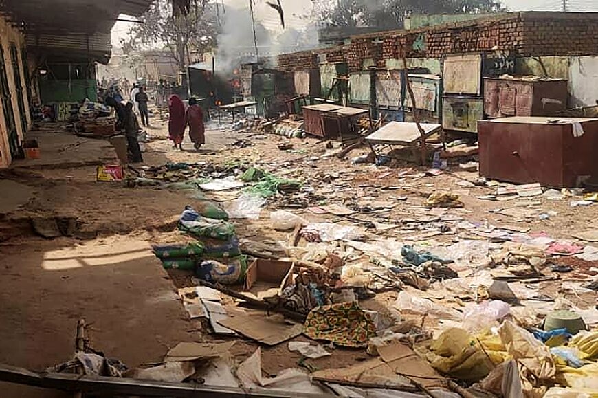 People walk among scattered objects in the market of El Geneina, West Darfur, where the UN said at least 96 people have been killed