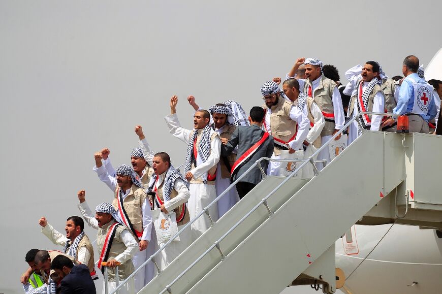 Yemeni Huthi prisoners gesture as they disembark  at Sanaa airport on April 15, part of a multi-day transfer that comes amid peace talks which have raised hopes for an end to Yemen's eight-year-old war