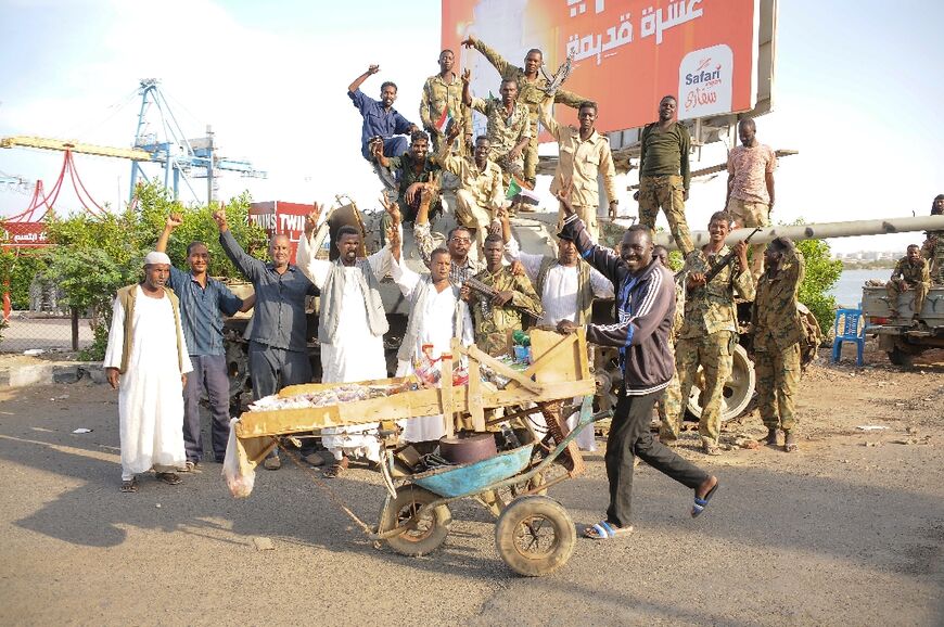 People cheer around Sudanese army soldiers, loyal to army chief Abdel Fattah al-Burhan, manning a position in the Red Sea city of Port Sudan, on April 20, 2023