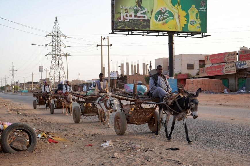Men ride donkey carts along an otherwise deserted street in Khartoum's twin city Omdurman on April 16 as fighting continues in Sudan