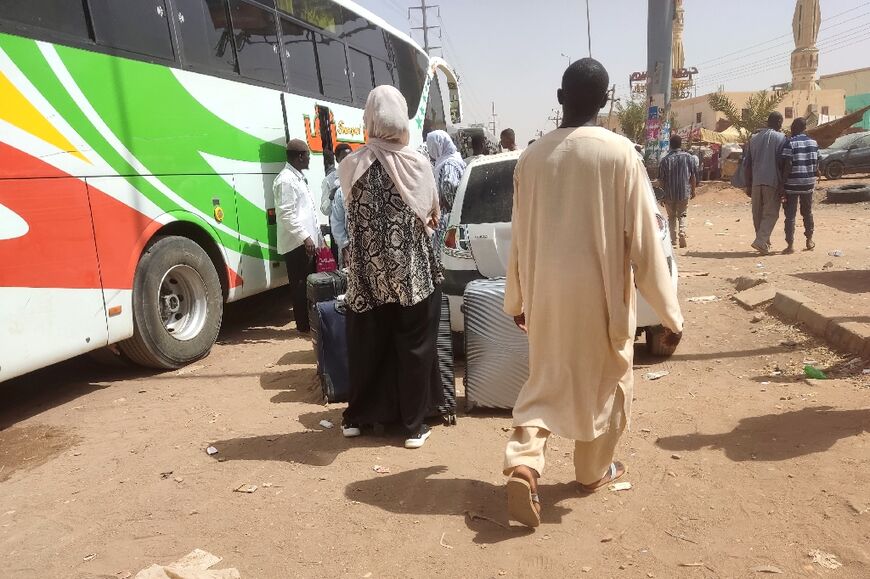 People gather at a bus station in southern Khartoum to flee the Sudanese capital